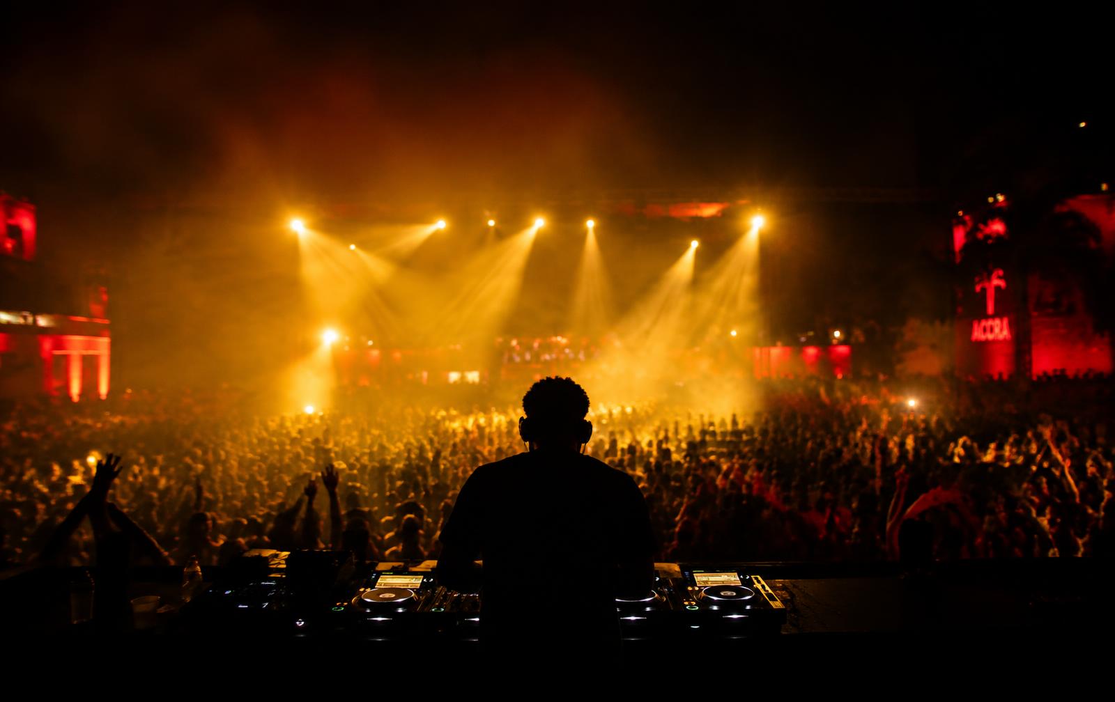 DJ performing to a packed crowd under gold stage lights
